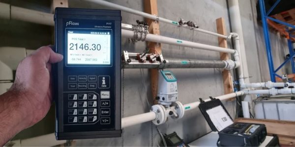 Ultrasonic flow meter calibration services: pFlow ultrasonic flowmeter displaying a reading of 2146.30. Pipes and additional calibration equipment visible.