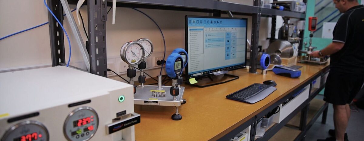 Calibration services: A technician performs calibration on pressure gauges in a lab setting with computer and testing equipment visible.